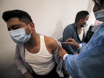 عراقي يتلقى جرعة من لقاح فايزر المضاد لفيروس كورونا في مركز للتحصين في بغداد، 25 أغسطس 2021 - AFP