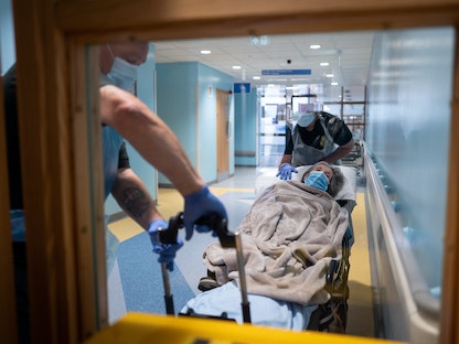 عناصر من خدمات نقل المرضى ينقلون مريضة مسنة غير مصابة بفيروس كوفيد-19 من المستشفى إلى دار رعاية بالقرب من بورتسموث، في بريطانيا، 5 مايو 2020 - REUTERS