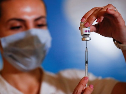 عاملة في المجال الصحي في بيونس آيرس بالأرجنتين تحمل جرعة من لقاح مضاد لفيروس كورونا - REUTERS