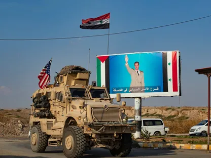 مدرعة أميركية عند نقطة تفتيش شمال شرقي سوريا بجانب صورة للرئيس بشار الأسد - AFP