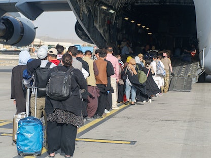 مجموعة من المغادرين قبل الصعود إلى متن طائرة أثناء عملية إخلاء في مطار حامد كرزاي الدولي، كابول أفغانستان - 18 أغسطس 2021. - REUTERS
