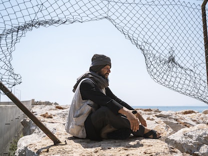 لاجئ أفغاني يجلس خلف سياج  - Getty Images