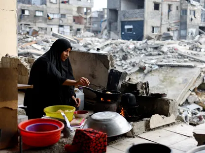 فلسطينية تعد طعاماً وسط حطام المباني السكنية المدمرة خلال الحرب الإسرائيلية في جباليا شمال قطاع غزة. 31 ديسمبر 2025 - REUTERS