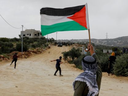متظاهر يحمل العلم الفلسطيني خلال اشتباكات مع القوات الإسرائيلية في نابلس بالضفة الغربية. 10 أبريل 2023 - REUTERS