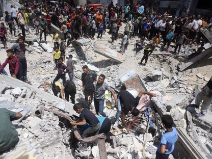 فلسطينيون بين أنقاض منازل دمرتها الغارات الإسرائيلية على رفح جنوبي قطاع غزة. 29 أبريل 2024 - AFP