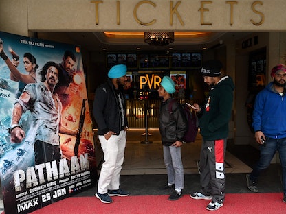 رواد السينما يقفون بجانب ملصق لفيلم بوليوود Pathaan، أمريتسار، 25 يناير 2023.  - AFP