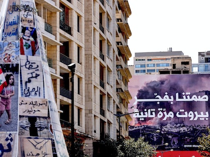 شعارات مناهضة للمؤسسات الرسمية اللبنانية ولوحة تدعو إلى المشاركة في الانتخابات وسط بيروت- 13 أبريل 2022 - AFP