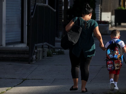 أم ترافق طفلها إلى المدرسة في اليوم الأول من الدارسة بمدينة نيويورك. 8 سبتمبر 2022 - REUTERS