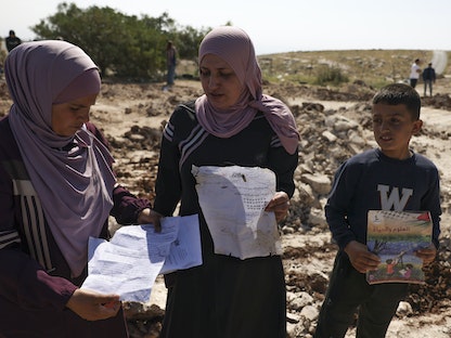 فلسطينيون يلتقطون أوراقاً وكتباً من موقع مدرسة هدمتها سلطات الاحتلال الإسرائيلي في قرية "جب الذيب" شرقي بيت لحم بالضفة الغربية. 7 مايو 2023 - AFP