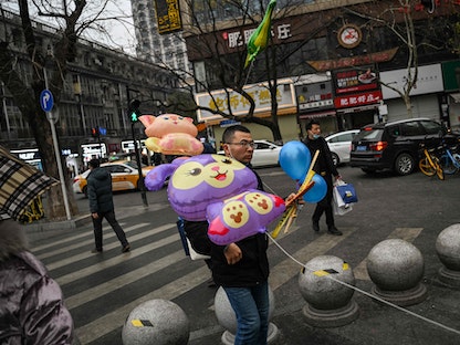 أشخاص يسيرون في أحد شوارع ووهان في مقاطعة هوبي بوسط الصين بالتزامن مع احتفالات رأس السنة القمرية. 21 يناير 2023 - AFP