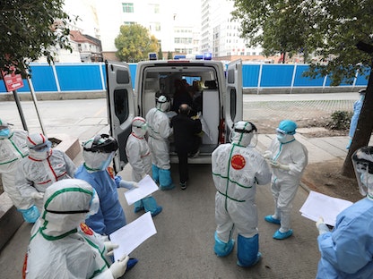 طاقم طبي برفقة مصاب بفيروس كورونا وهو يغادر مستشفى ووهان في الصين - 4 مارس 2020 - AFP