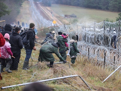 مهاجرون يتجمعون بالقرب من سياج أسلاك شائكة بمنطقة غرودنو في بيلاروسيا، في محاولة لعبور الحدود مع بولندا  - 8 نوفمبر 2021 - REUTERS