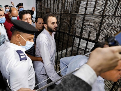 محمد عادل المتهم بقتل طالبة جامعة المنصورة نيرة أشرف محاط بالحراس أثناء إخراجه من صندوق الاتهام - 26 يونيو 2022 - AFP