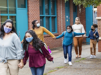 عدد من الأطفال يرتدون أقنعة واقية مع أمهاتهم بعد عودة الدراسة التي توقفت بسبب انتشار فيروس كورونا في الولايات المتحدة - Getty Images