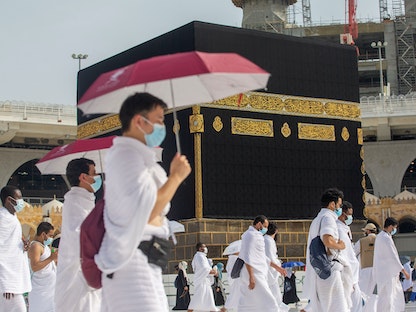 حجاج يرتدون أقنعة الوجه ويحافظون على مسافة اجتماعية يؤدون الطواف حول الكعبة أثناء موسم الحج عام 2020 - VIA REUTERS