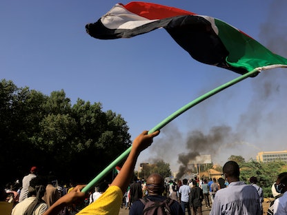 متظاهر في العاصمة الخرطوم يرفع علم السودان - 9 يناير 2022 - REUTERS