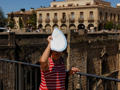 امرأة تستخدم مروحة لتغطية رأسها من أشعة الشمس الحارقة في روندا بإسبانيا. 26 أبريل 2023 - REUTERS