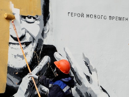 عامل يزيل لوحة جدارية للمعارض الروسي أليكسي نافالني في سان بطرسبرغ. 28 أبريل 2021  - REUTERS