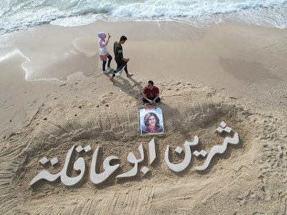 اسم الصحفية الفلسطينية الأميركية "شيرين أبو عقلة" مخطوط على رمال أحد شواطئ مدينة غزة- 11 مايو 2022.  - REUTERS