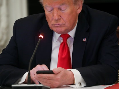 الرئيس الأميركي السابق دونالد ترمب يتفقد هاتفه - REUTERS