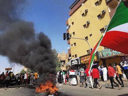 متظاهرون يحملون أعلام السودان خلال احتجاجات تطالب بسلطة مدنية - 9 يناير 2022  - AFP