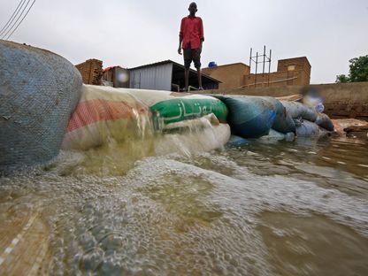 سوداني يقف خلف حاجز وسط مياه الفيضانات في جزيرة توتي بالعاصمة الخرطوم - AFP