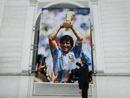 صورة معلقة على جدار السفارة الأرجنتينية في بوليفيا للراحل دييجو مارادونا وهو يحمل كأس العالم - REUTERS