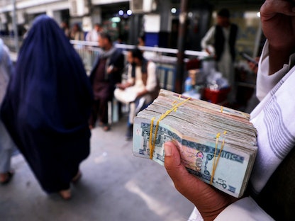 أفغاني يحمل حزمة من الأوراق النقدية في سوق للصرافة بكابول بعد سيطرة طالبان على مقاليد الأمور في أفغانستان - 4 سبتمبر 2021 - REUTERS