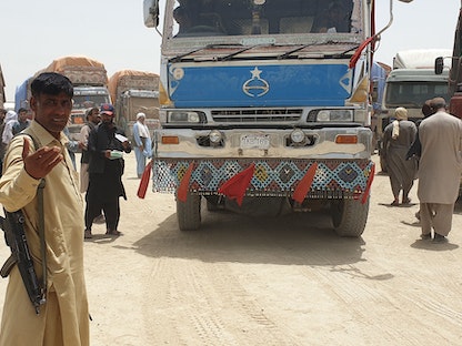 حراس يرتدون ملابس مدنية بينما تستعد شاحنات البضائع للتوجه نحو نقطة العبور عند الحدودية الأفغانية في شامان - 27 يوليو 2021 - AFP