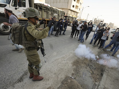 جندي إسرائيلي يستخدم قنبلة صوتية أثناء تفريقه للصحافيين في بلدة حوارة الفلسطينية بالقرب من نابلس بالضفة الغربية. 27 فبراير 2023 - AFP