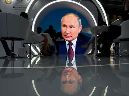 الرئيس الروسي فلاديمير بوتين يظهر على شاشة تعرض خطابه أمام منتدى سانت بطرسبرغ الاقتصادي الدولي - AFP