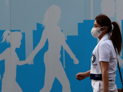 سيدة متطوعة في أولمبياد طوكيو تضع كمامة  - REUTERS