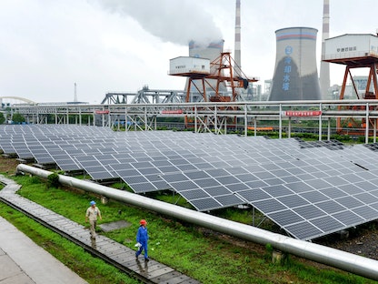 موظفون يفحصون ألواحاً شمسية أثناء عملهم في مشروع توليد طاقة كهروضوئية متصل بشبكة محطة طاقة في مقاطعة تشانجشينج، الصين - 13 يونيو 2017 - REUTERS