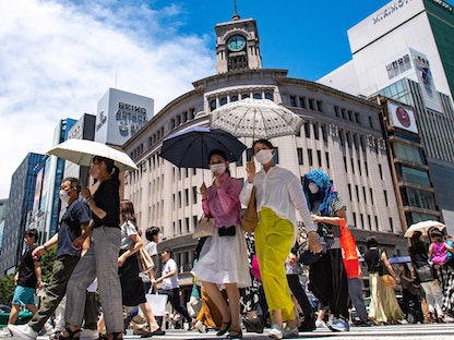 مشاة يسيرون في شارع بمنطقة جينزا بطوكيو - 26 يونيو 2022 - AFP