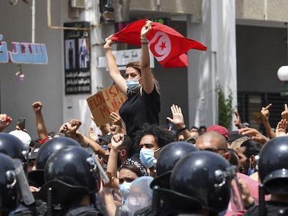 متظاهرة ترفع العلم التونسي خلال احتجاجات مناهضة للحكومة أمام مقر البرلمان في العاصمة تونس - 25 يوليو 2021 - AFP