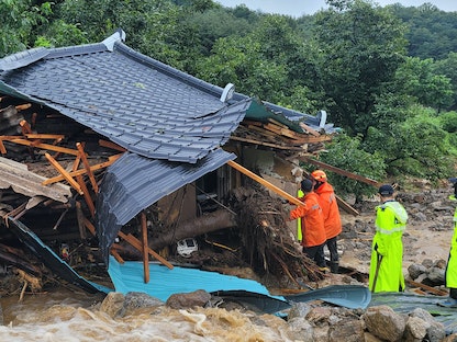 عمال طوارئ في كوريا الجنوبية يبحثون عن ناجين في منزل دمرته مياه الفيضانات في يتشيون. 15 يوليو 2023 - AFP
