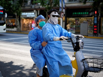 مواطنان صينيان يرتديان ملابس واقية ضد العدوى في شنغهاي فيما تعاني المدينة تفشي فيروس كورونا، الصين- 15 يونيو 2022 - REUTERS