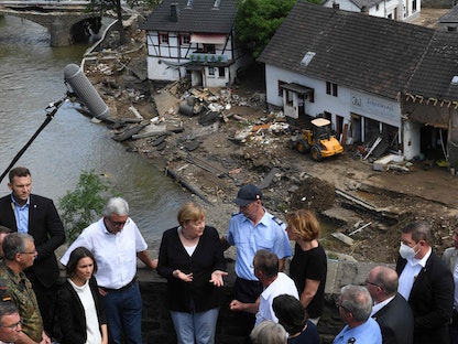 المستشارة الألمانية أنغيلا ميركل ورئيس وزراء ولاية راينلاند بالاتينات مالو دريير يتحدثان إلى السكان خلال زيارتهما للمناطق التي دمرتها الفيضانات في شولد غرب ألمانيا، 18 يوليو 2021 - AFP