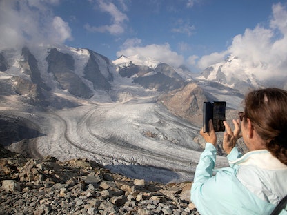 امرأة تلتقط صورة لنهر بيرس الجليدي من نقطة مراقبة في منطقة ديافوليزا بالقرب من منتجع بونتريسينا في جبال الألب السويسرية. 21 يوليو 2022 - REUTERS
