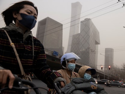 أناس يرتدون أقنعة وجه في يوم ملوث بالعاصمة الصينية بكين. 10 مارس 2023 - REUTERS