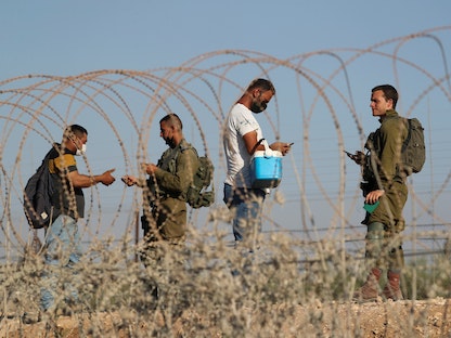جنود إسرائيليون يفحصون وثائق الفلسطينيين أثناء عودتهم إلى الضفة الغربية. 6 سبتمبر 2021 - REUTERS