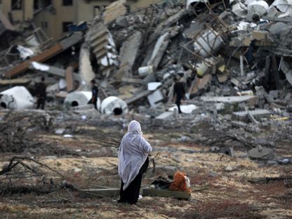 فلسطينية تجمع بعض ما تبقى من حطام منزلها الذي درمته غارة إسرائيلية على رفح في قطاع غزة بفلسطين. 25 مارس 2024 - AFP