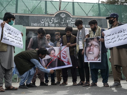 متظاهرون أفغان يحرقون ملصقاً للرئيس الإيراني إبراهيم رئيسي أثناء احتجاج أمام السفارة الإيرانية في كابول- 11 أبريل 2022 - AFP