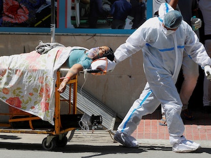 عامل صحي يجر سريراً يحمل مريضة مصابة بفيروس كورونا في مستشفى جورو تيج بهادور في نيودلهي - 24 أبريل 2021 - REUTERS