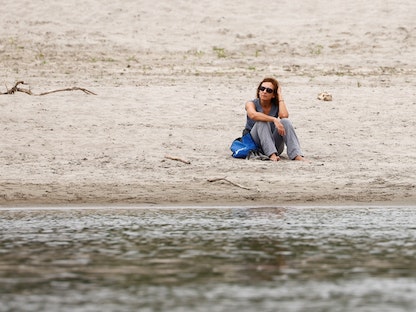امرأة تجلس على مجرى نهر بو أطول نهر في إيطاليا بعد أن جفت أجزاء منه - 22 يونيو 2022 - REUTERS