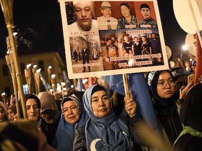 أنصار الأقلية المسلمة من الإيغور يحملون مشاعل ولوحات الأشخاص الذين قتلوا في معسكرات إعادة التأهيل في الصين، 20 ديسمبر 2019 - AFP