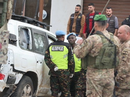 عناصر من الجيش اللبناني وأفراد من قوات اليونيفيل يقفون بجانب المركبة التي تعرضت لإطلاق نار في بلدة العاقبية جنوب لبنان، 15 ديسمبر 2022 - REUTERS