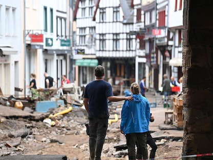 زوجان ينظران إلى الخراب الذي تسببت به الفيضانات في باد موينستريفيل غرب ألمانيا، 16 يوليو 2021 - AFP