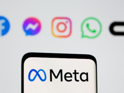شعار شركة ميتا على شاشة هاتف أمام شعارات فيسبوك وواتساب وإنستجرام وماسنجر وأوكولوس - REUTERS