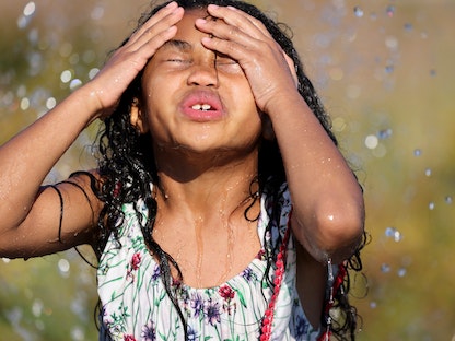 طفلة تلعب بالمياه خلال موجة حرّ في مدينة سياتل بولاية واشنطن الأميركية- 27 يونيو 2021 - REUTERS